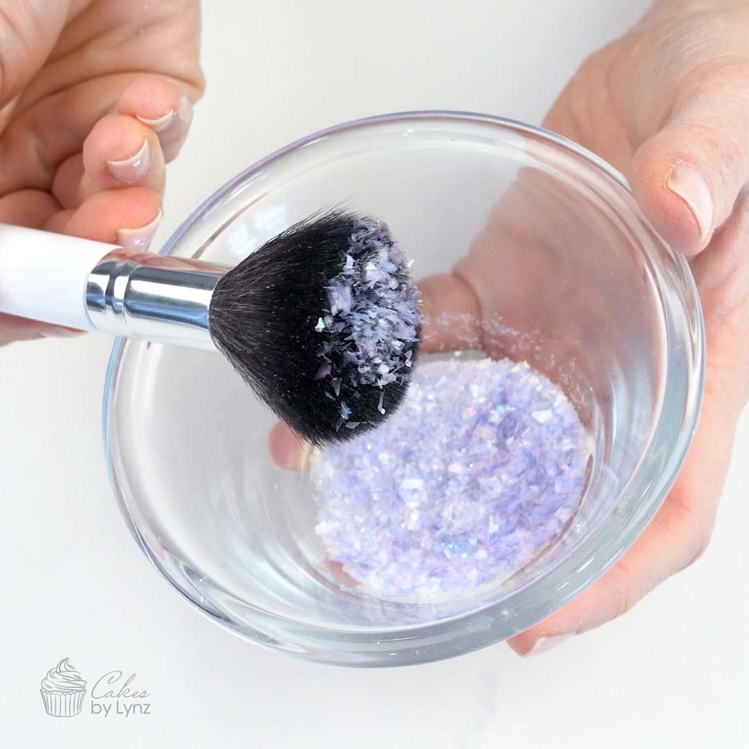 Picking up edible glitter with a large fluffy brush